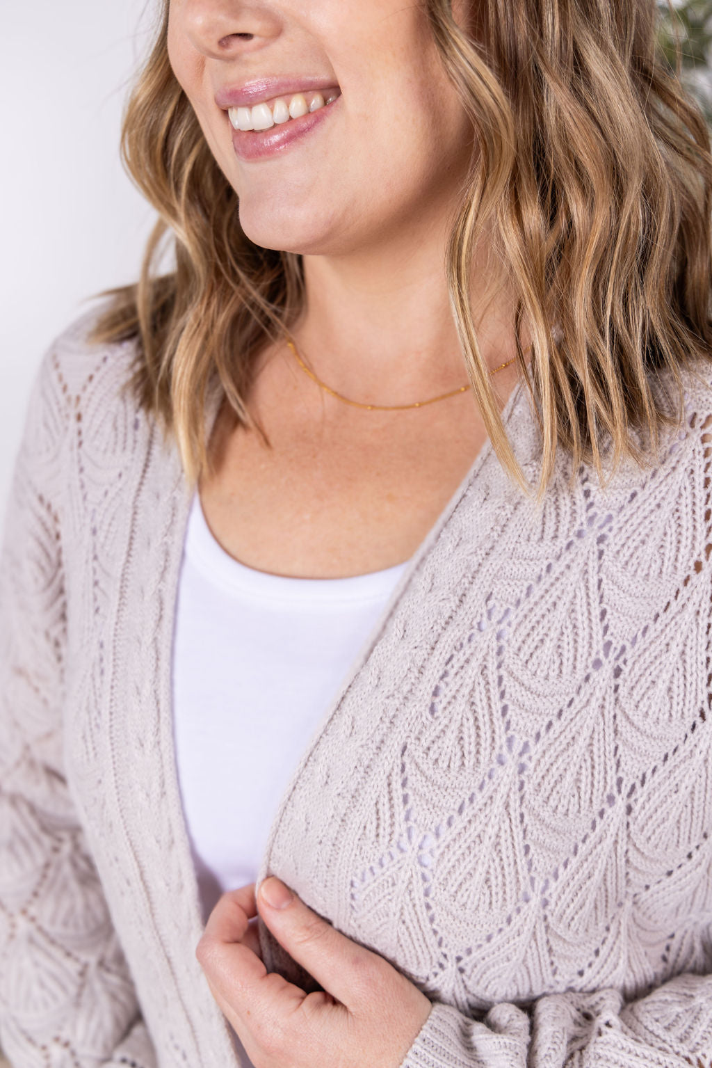 Neutral open knit cardigan with two pockets and airy textured pattern