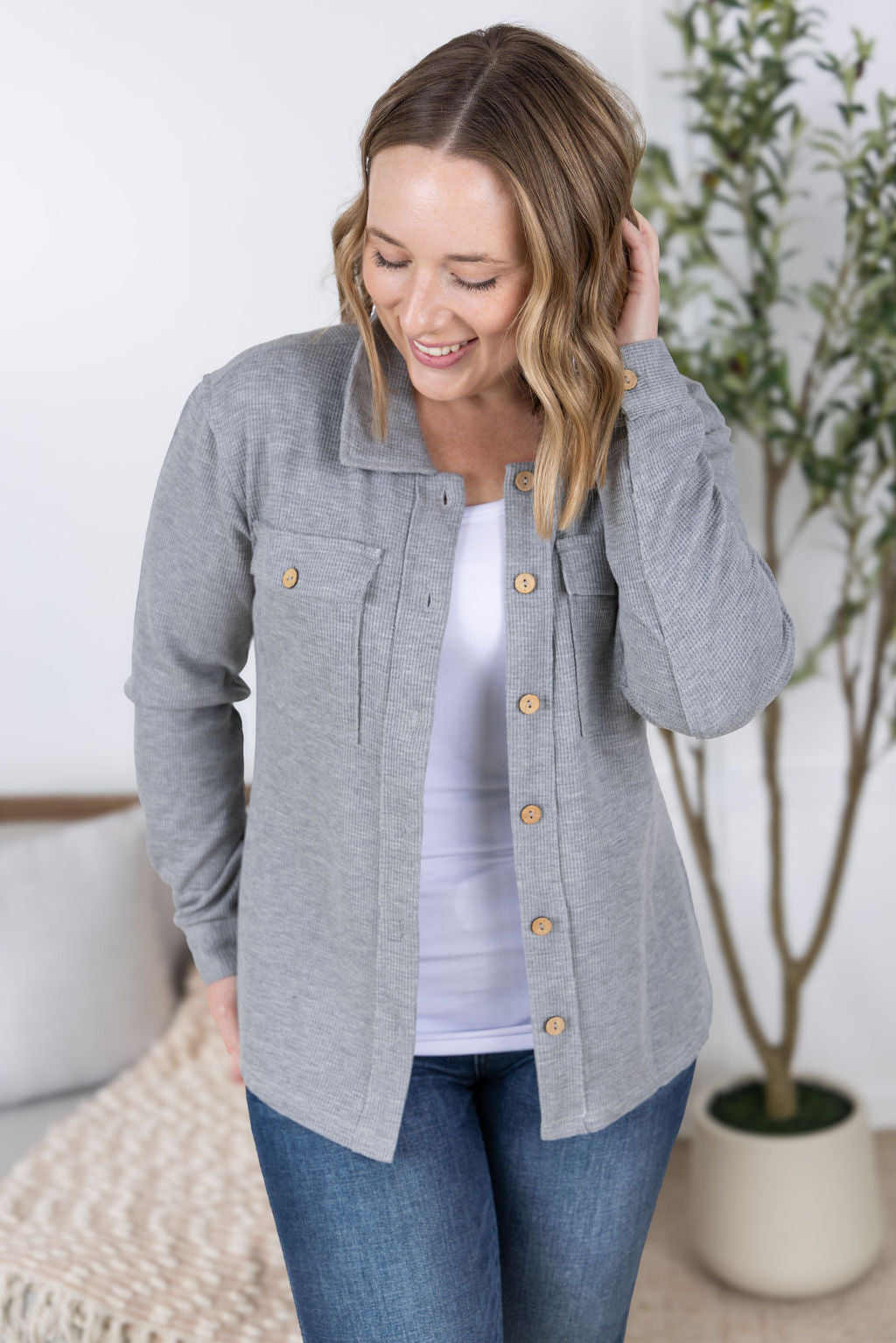 Woman wearing grey waffle knit button top with long sleeves and chest pockets.