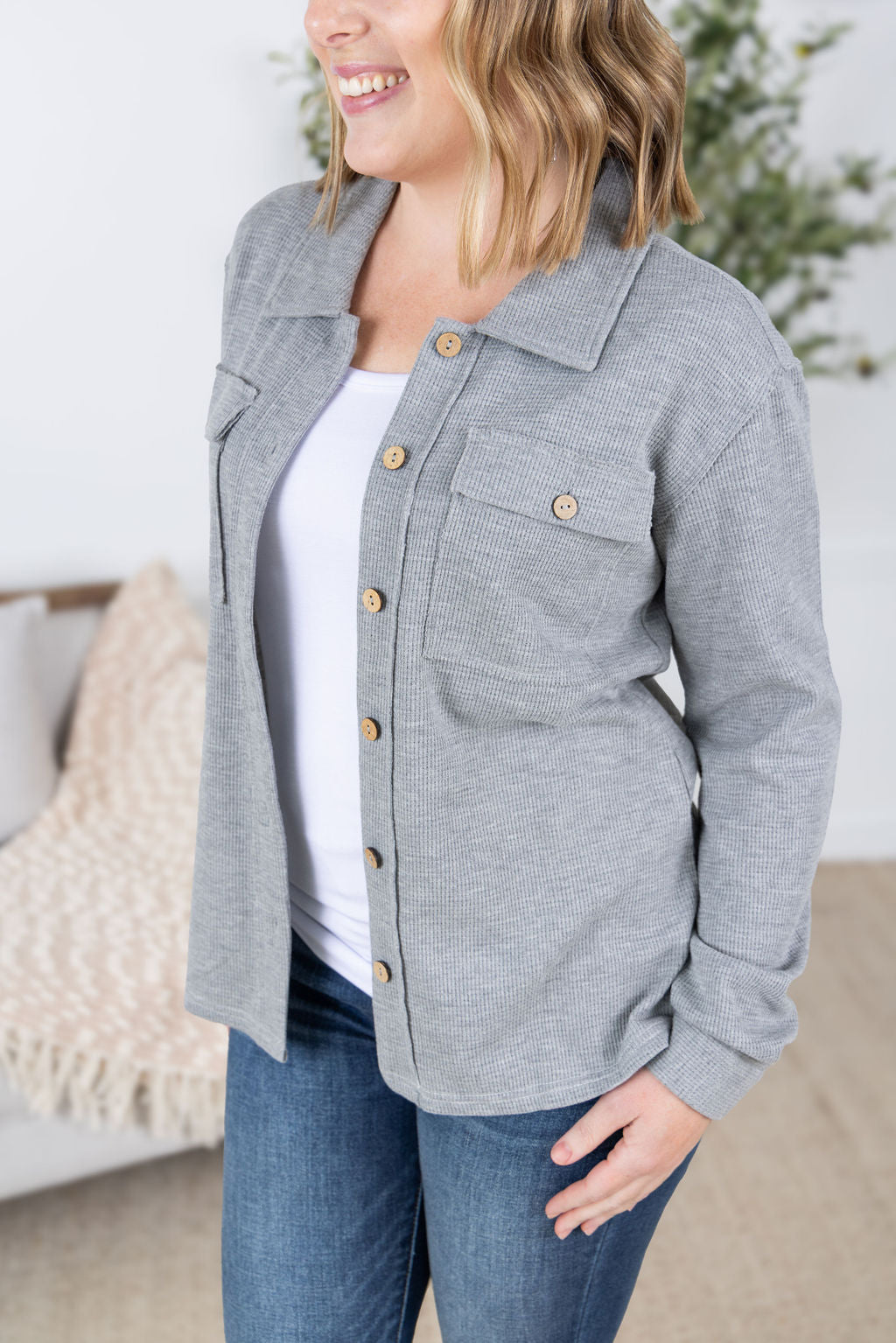 Woman wearing grey waffle knit button top with long sleeves and chest pockets.