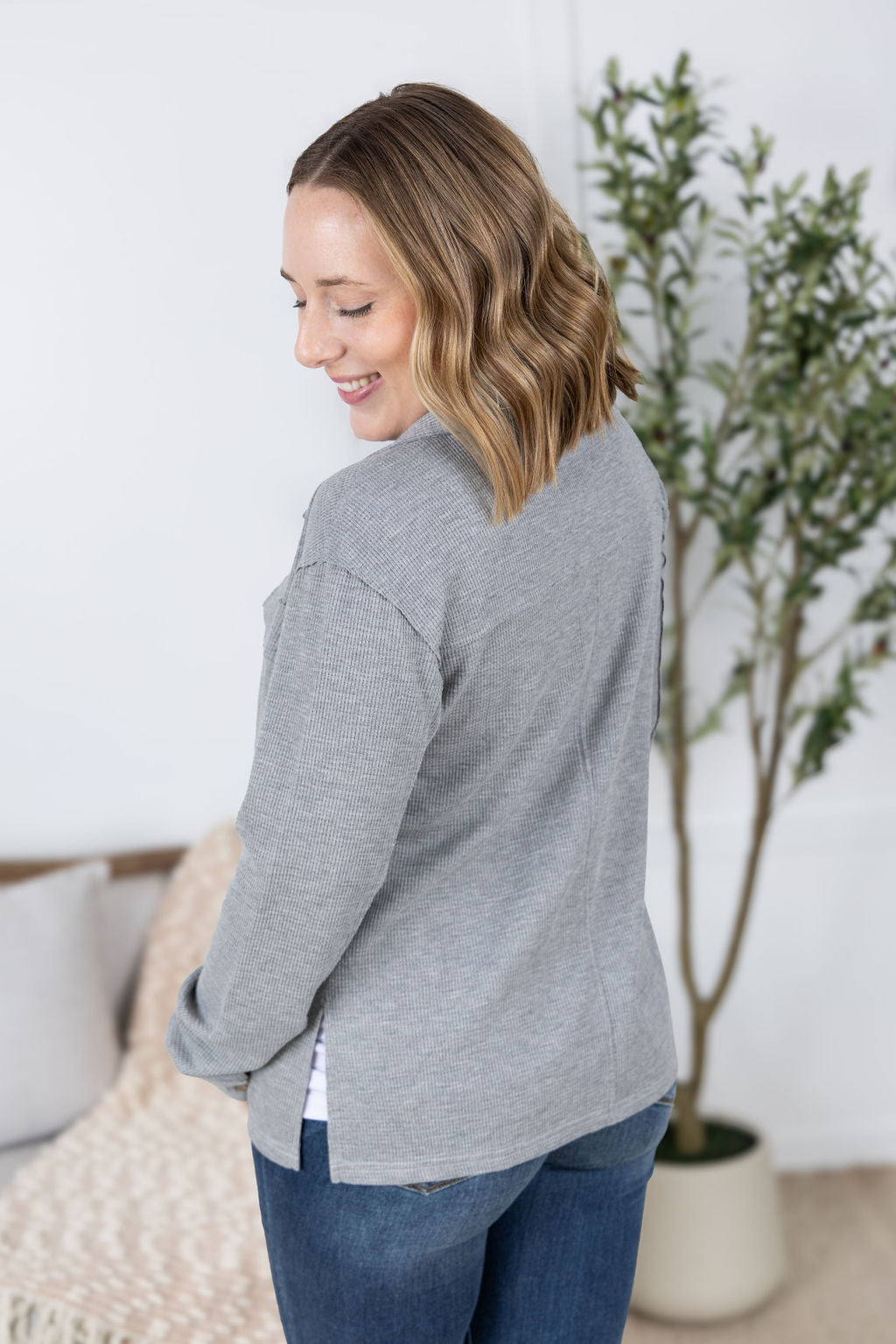 Woman wearing grey waffle knit button top with long sleeves and chest pockets.