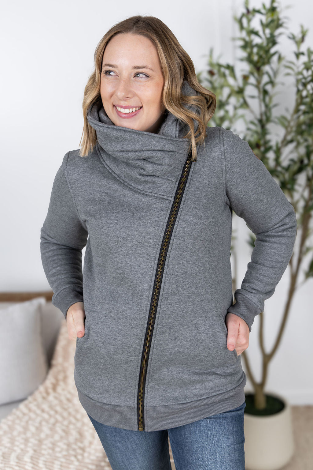 Woman wearing the Quinn ZipUp Cowl hoodie in gray with asymmetrical zipper