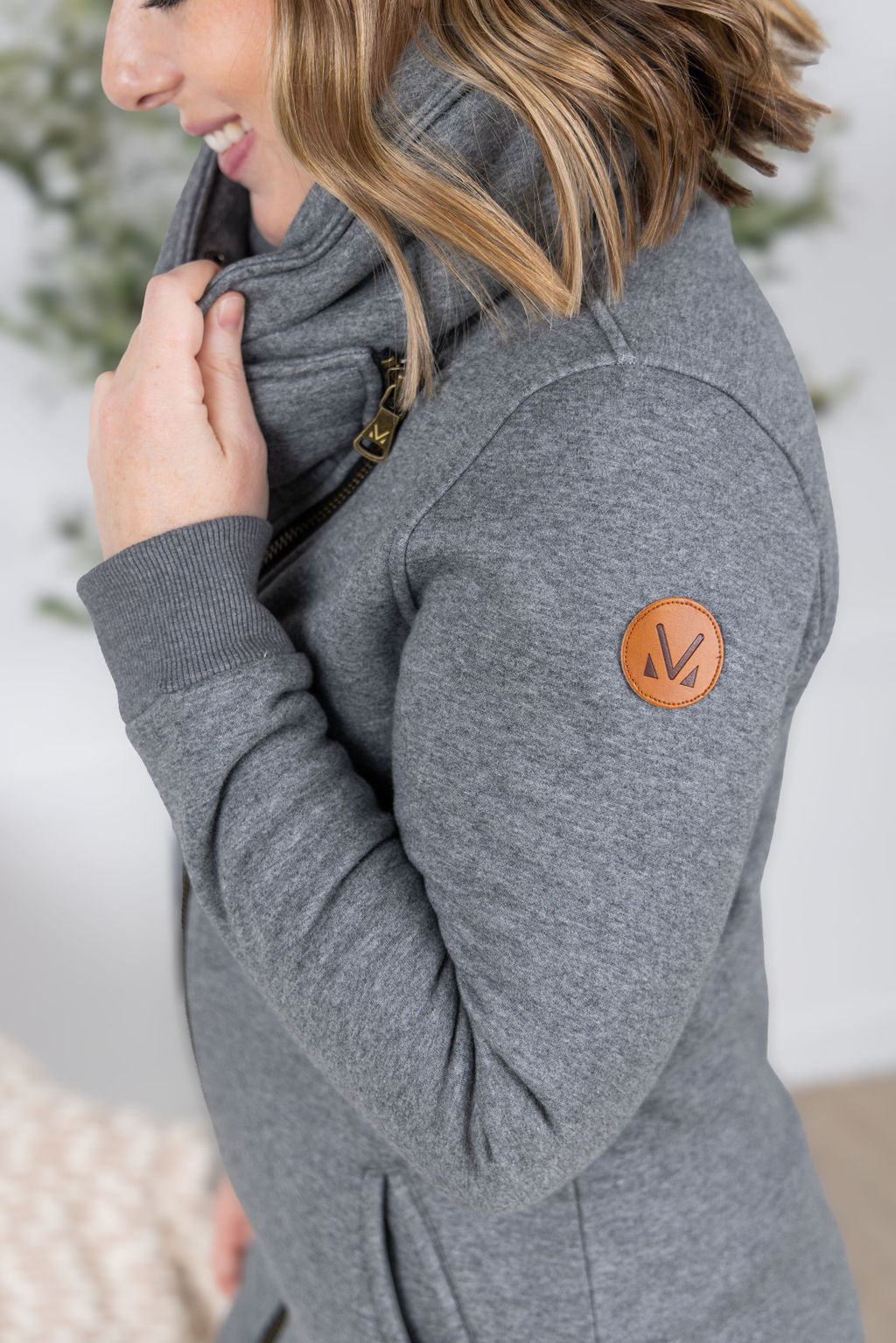 Woman wearing the Quinn ZipUp Cowl hoodie in gray with asymmetrical zipper