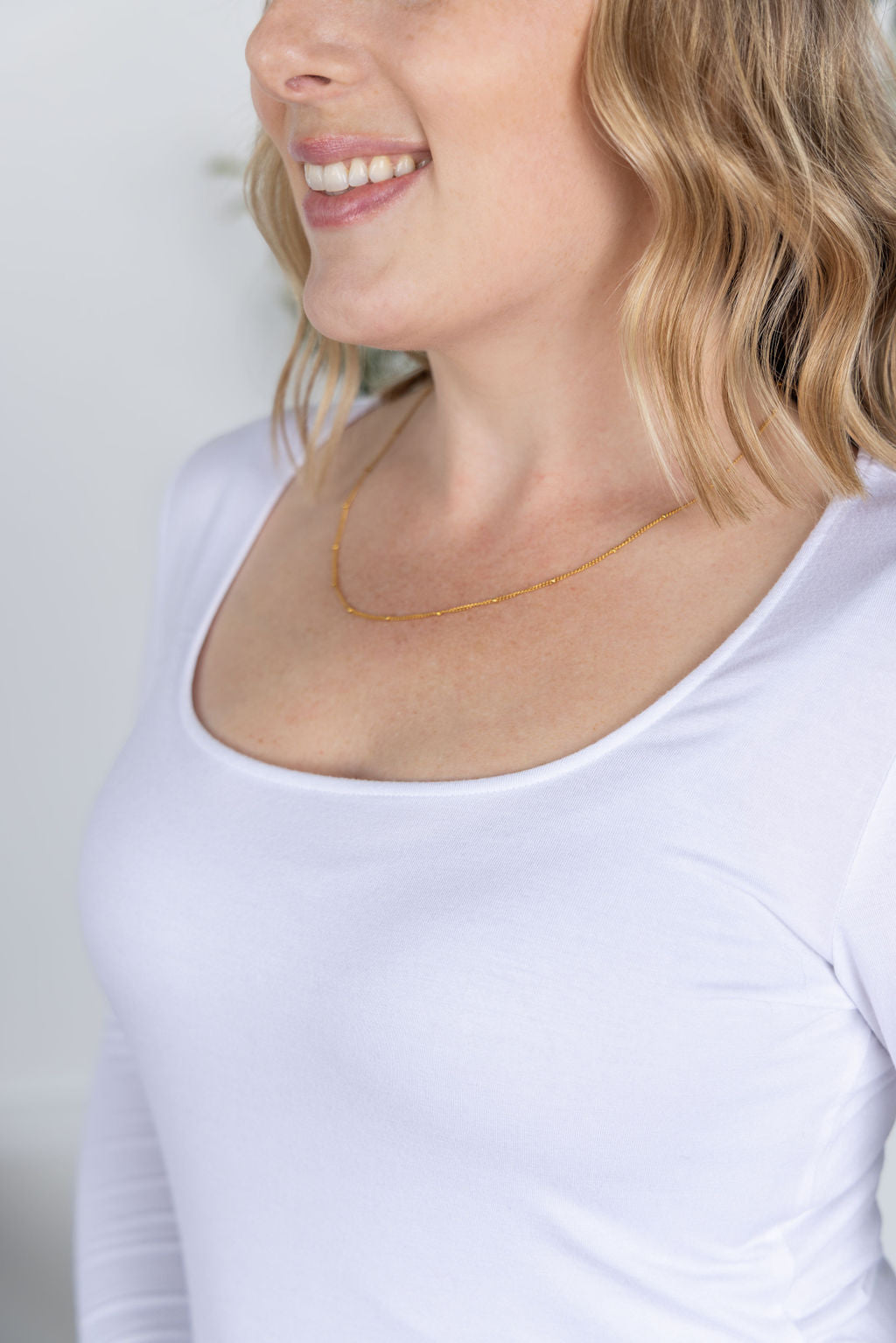Woman wearing Alyssa Long Sleeve Top in white with scoop neckline