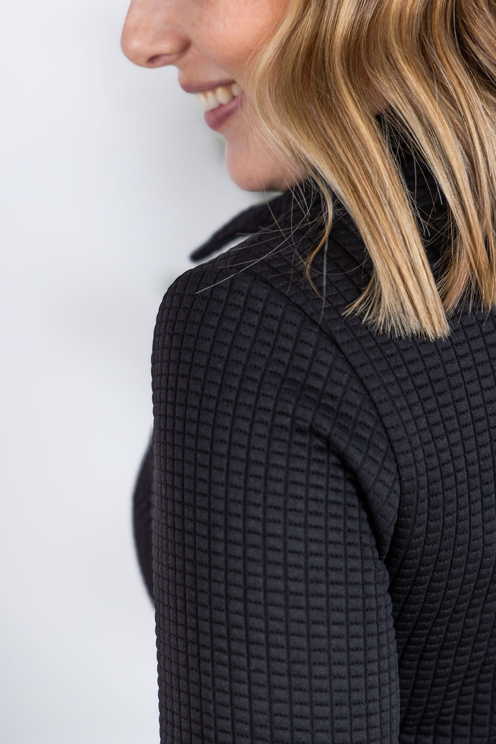 Woman wearing black Whitley Waffle Snap Pullover with waffle knit, snap buttons, and kangaroo pocket.
