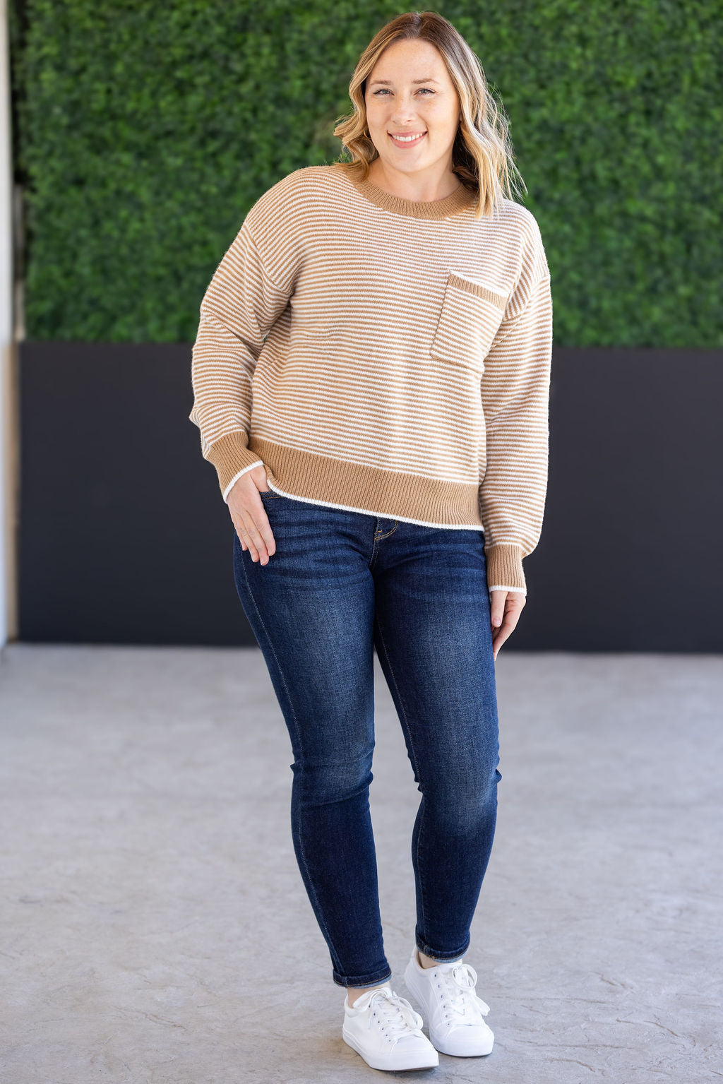 Woman wearing ivory and latte striped sweater with front pocket
