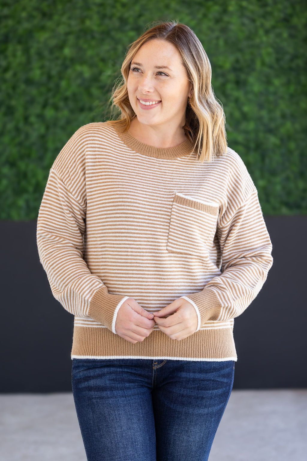 Woman wearing ivory and latte striped sweater with front pocket
