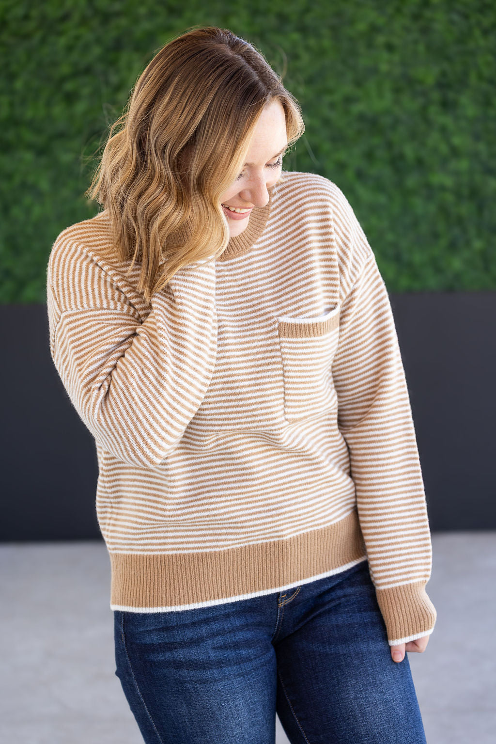 Woman wearing ivory and latte striped sweater with front pocket