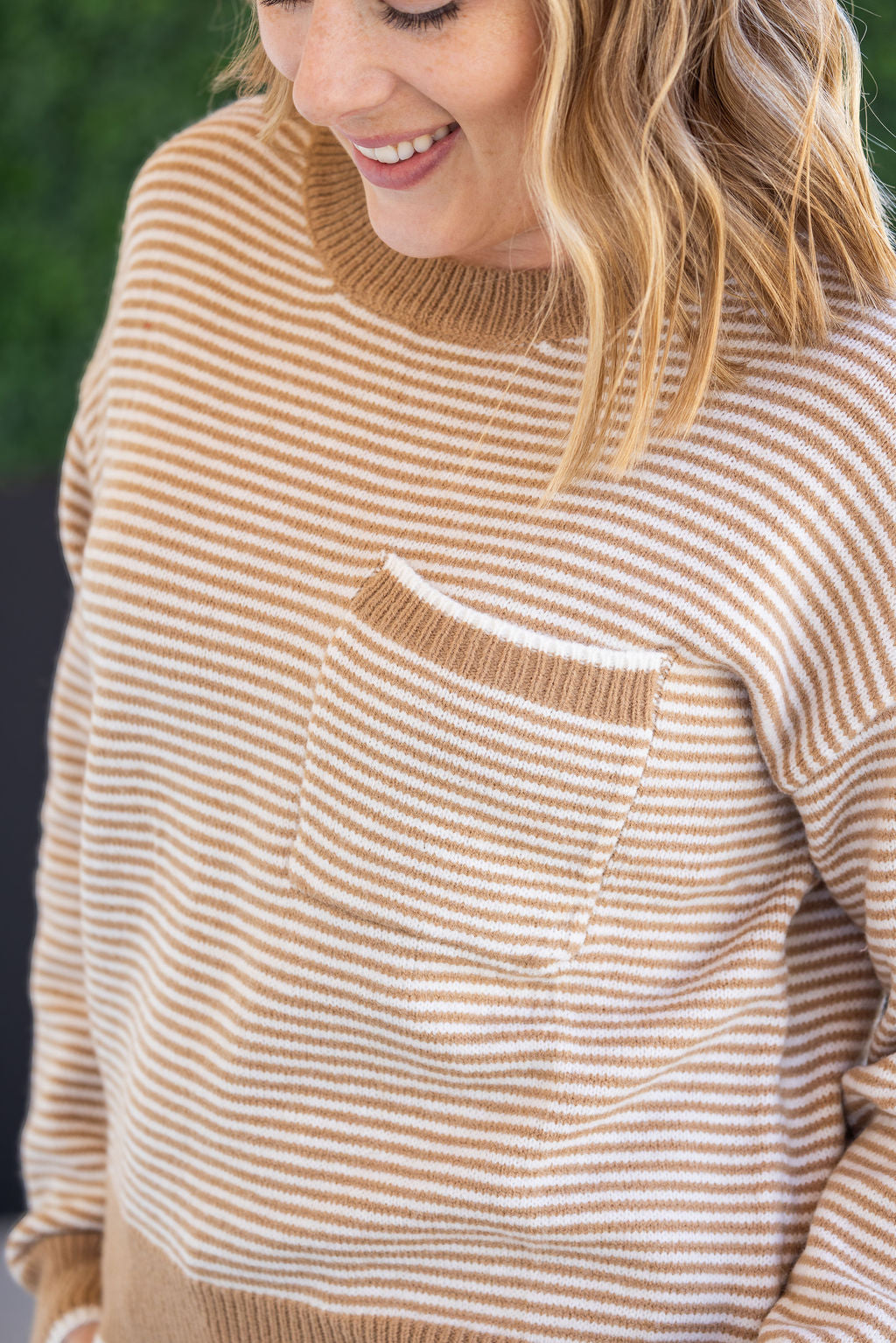 Woman wearing ivory and latte striped sweater with front pocket