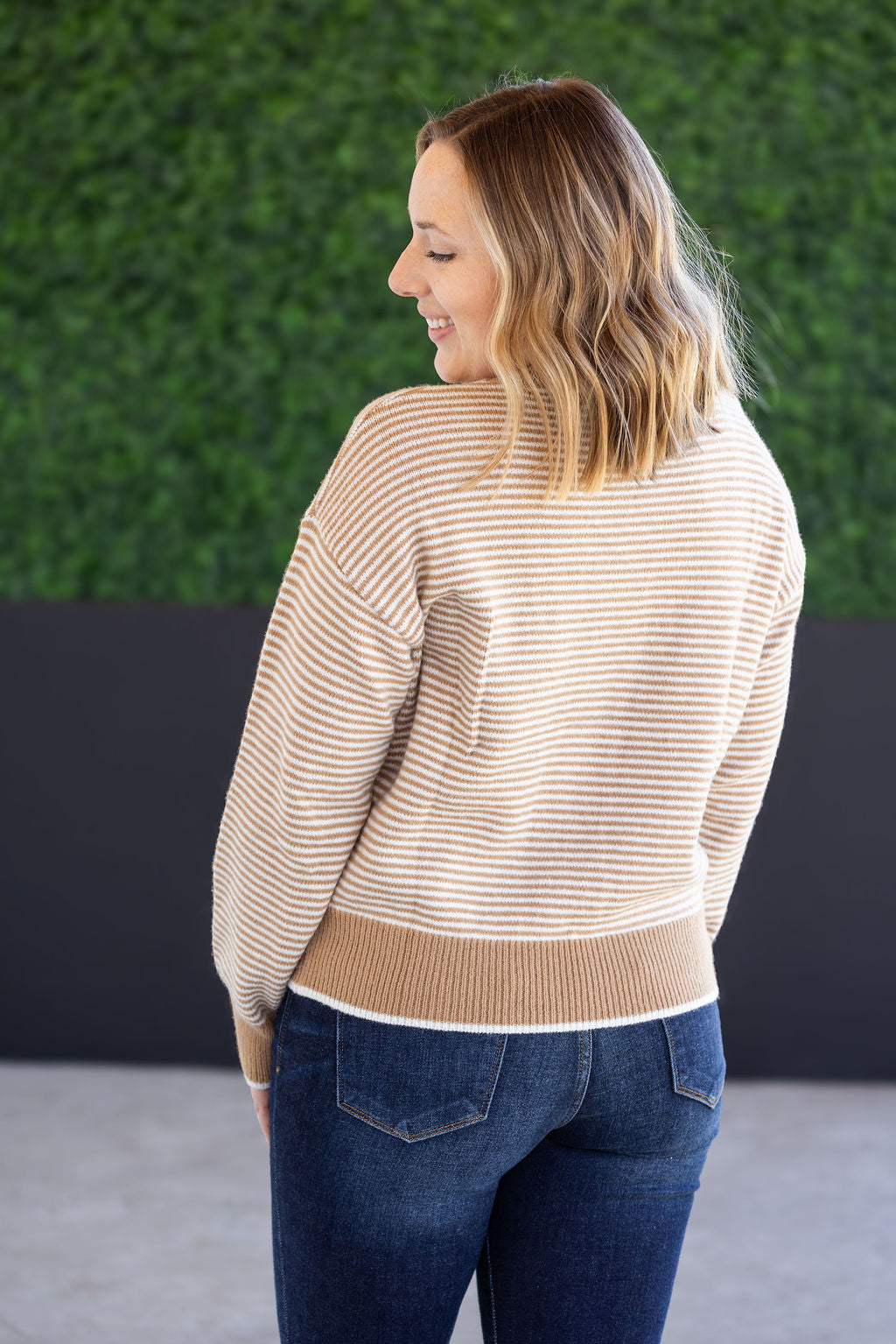 Woman wearing ivory and latte striped sweater with front pocket