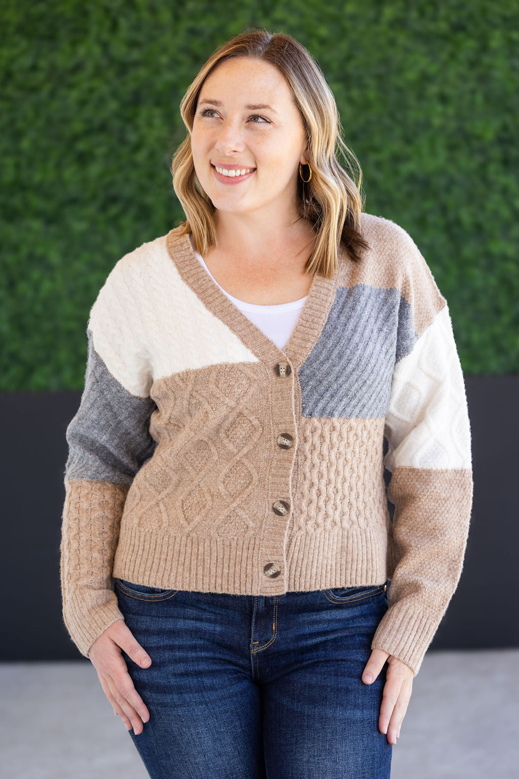 Woman wearing a patchwork sweater with a green wall background