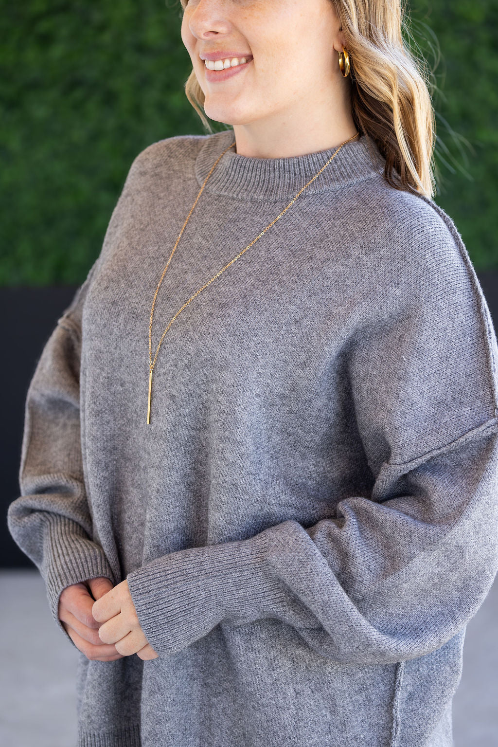 Woman wearing the Aurora Cozy Sweater in gray with mock neck, seam detail, and side slits.