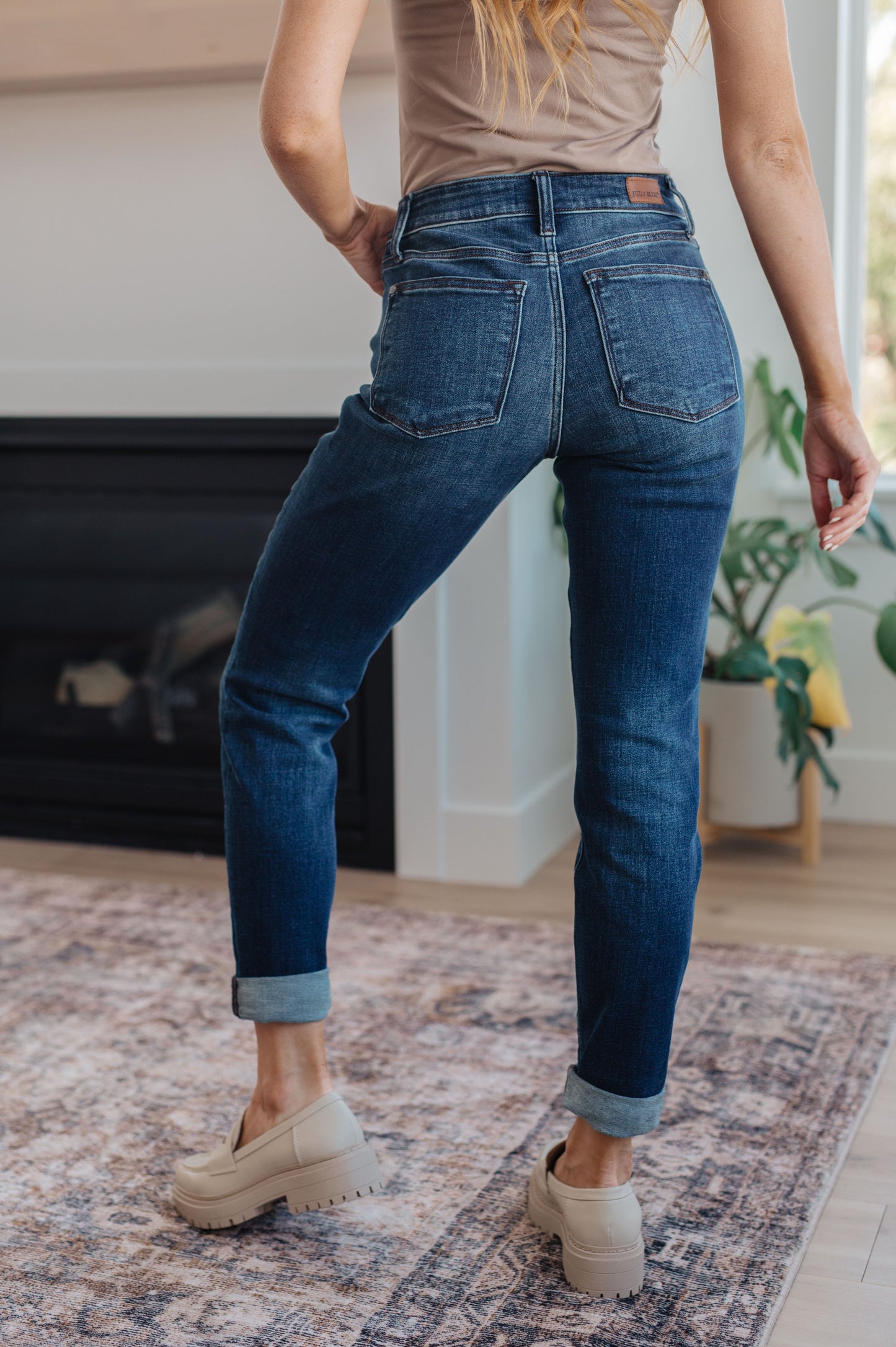 Model wearing dark wash slim fit jeans with cuffed hem and loafers