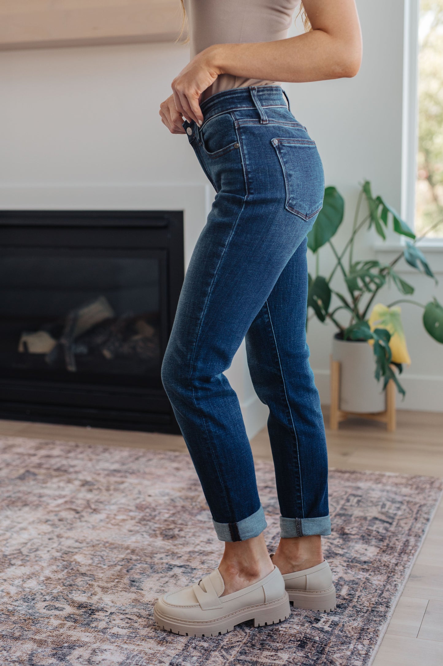 Model wearing dark wash slim fit jeans with cuffed hem and loafers