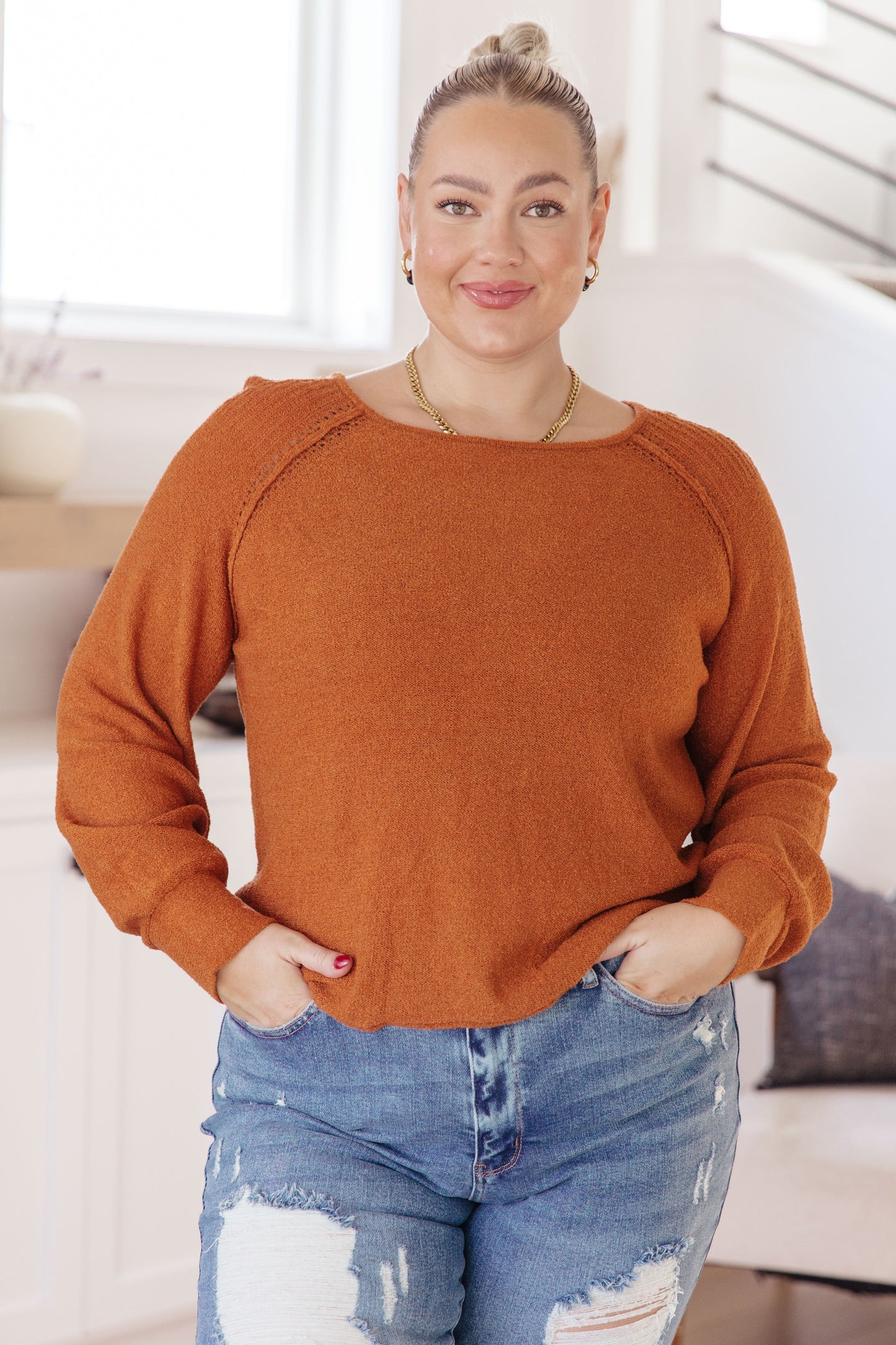 Woman wearing Autumn Glow Pullover Sweater in burnt orange with raglan sleeves and exposed seams.