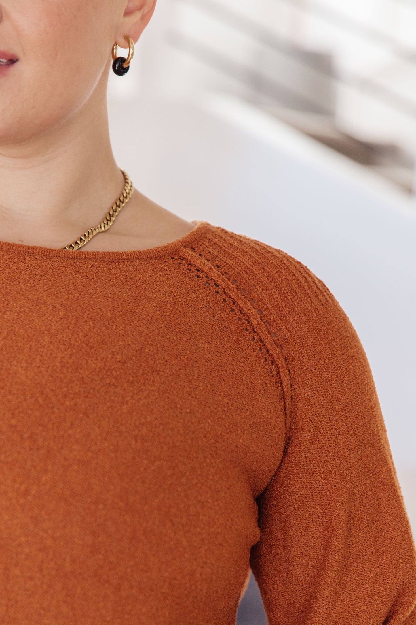 Woman wearing Autumn Glow Pullover Sweater in burnt orange with raglan sleeves and exposed seams.