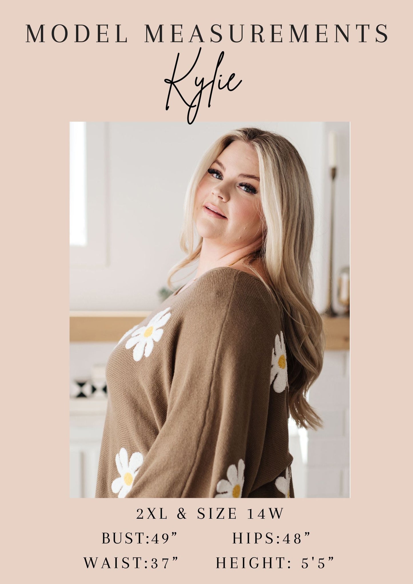 Kylie wearing a brown cardigan with white floral patterns, standing in a kitchen.