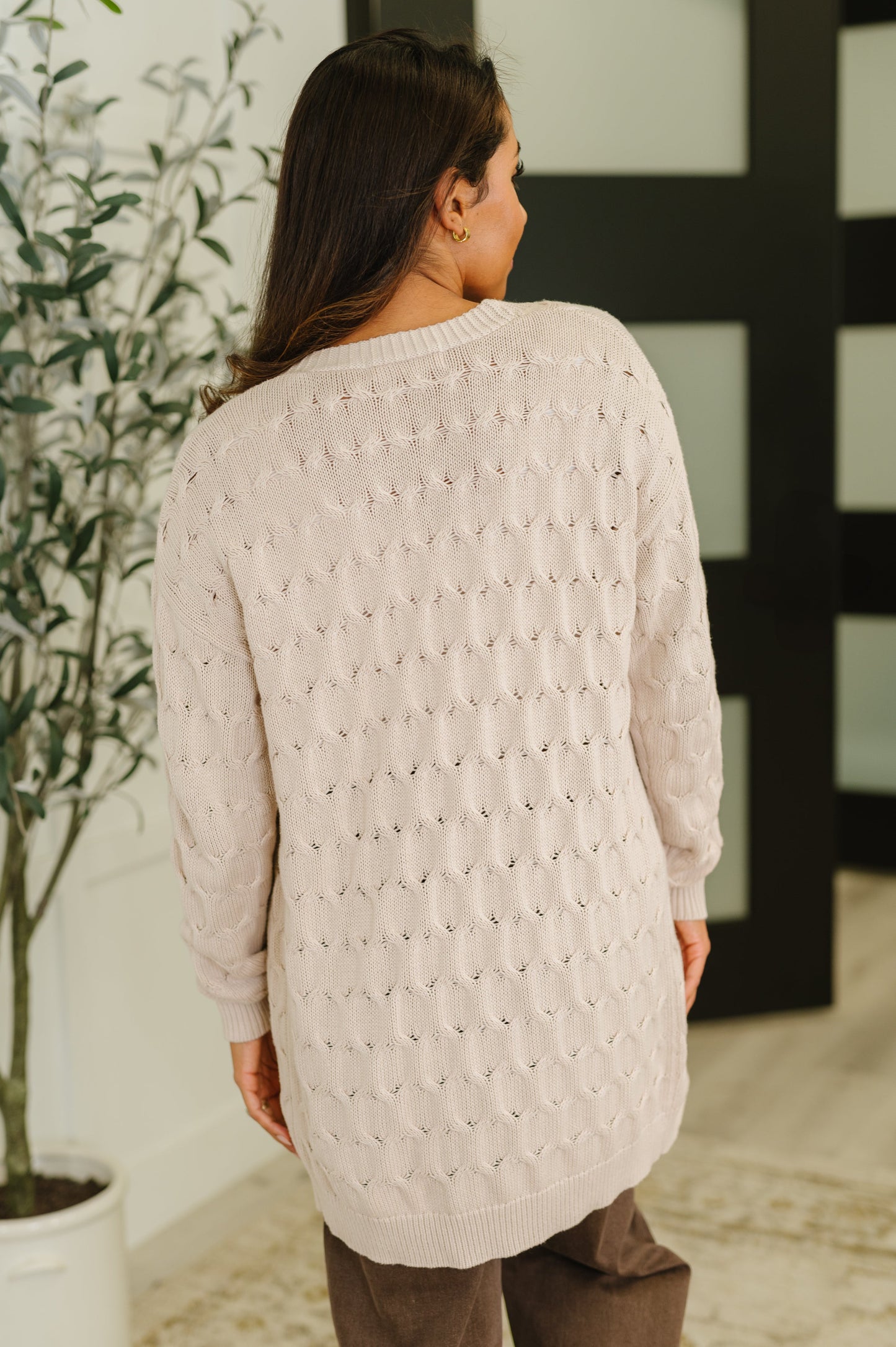 Woman wearing the Laugh Airily Cable Knit Cardigan in beige with open front and patch pockets.