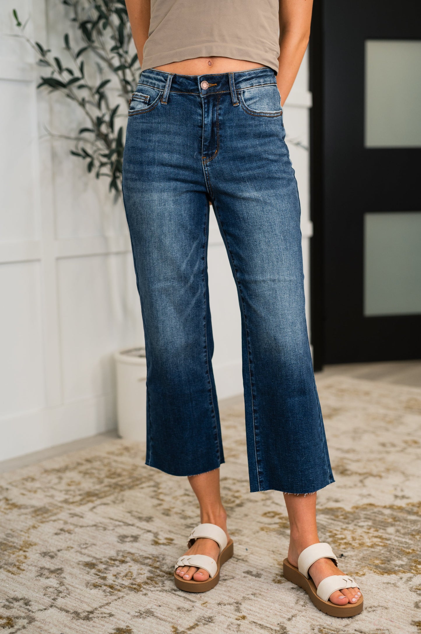 Woman wearing dark wash Maisie High Waist Crop Wide Jeans with raw hem and wide leg