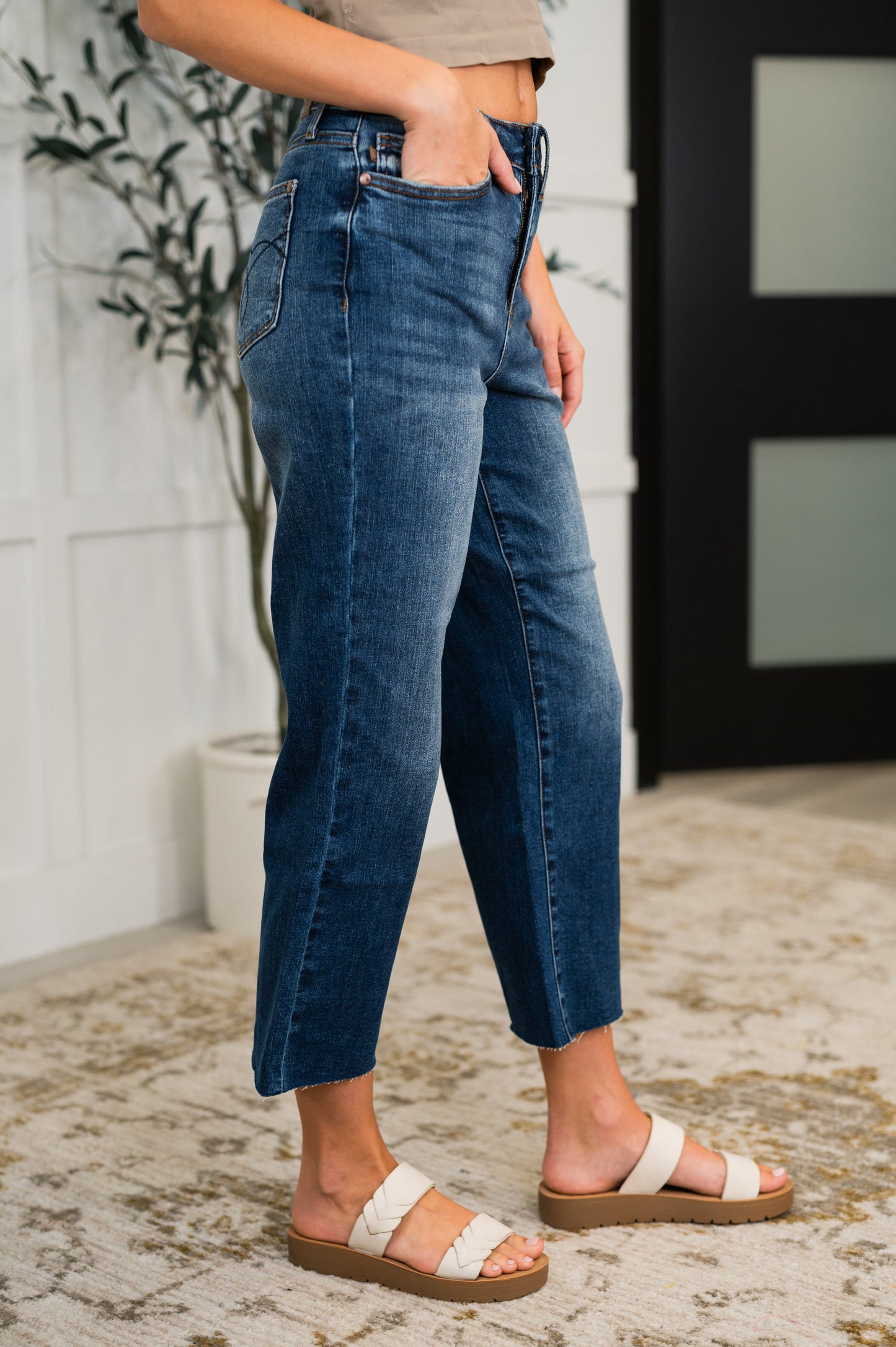 Woman wearing dark wash Maisie High Waist Crop Wide Jeans with raw hem and wide leg