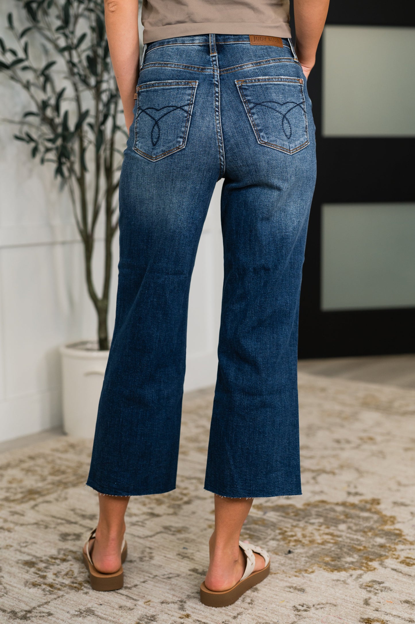 Woman wearing dark wash Maisie High Waist Crop Wide Jeans with raw hem and wide leg