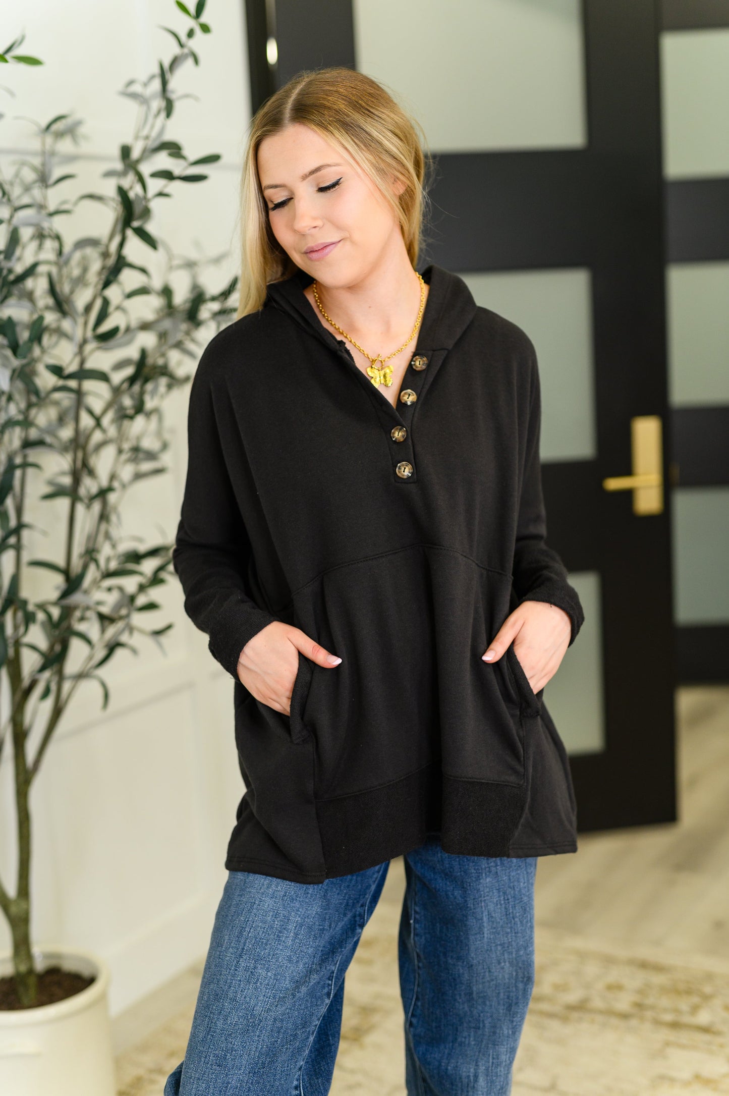 Black Henley pullover hoodie with kangaroo pocket, thumb holes, and contrast details