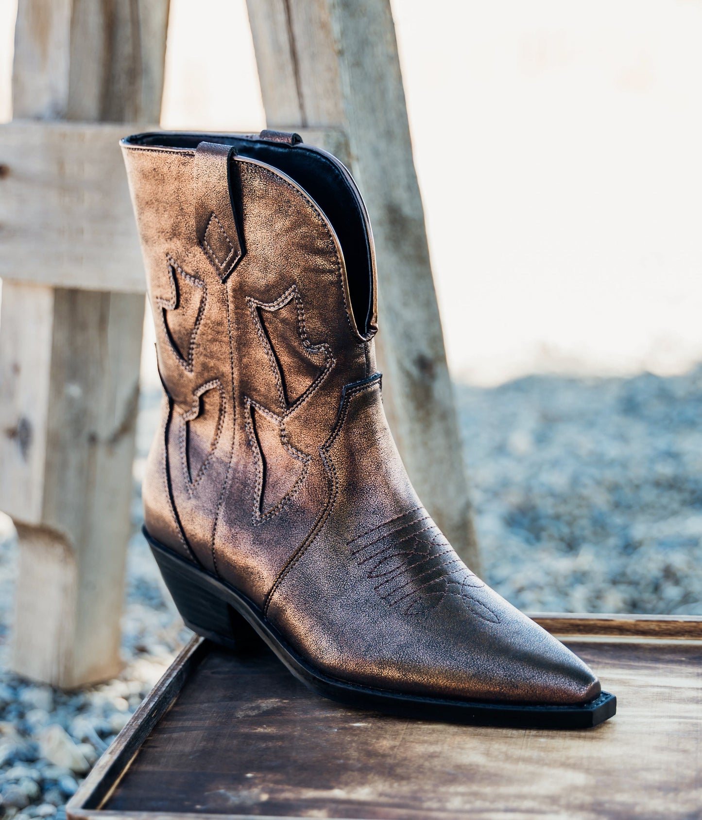 Metallic bronze cowboy boots with snip toe, mid-rise shaft, and western stitching