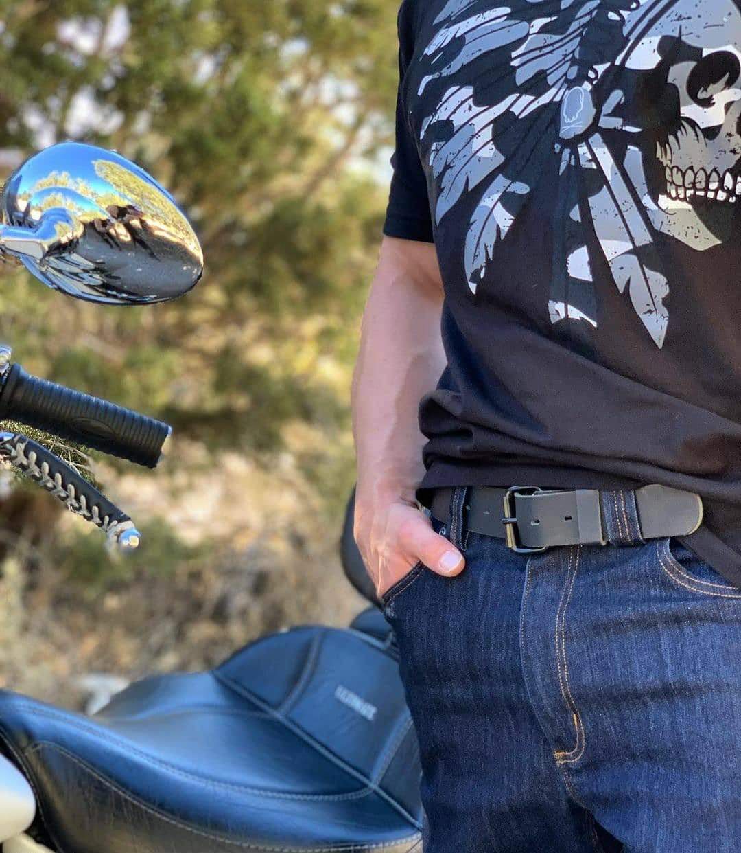 Person wearing a black t-shirt with a skull design, sitting on a motorcycle.