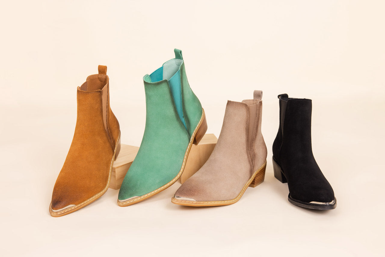 Four pairs of ankle boots in different colors on a beige background