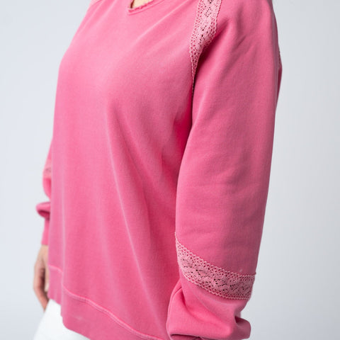 Woman in a cozy maroon top, smiling and posing in a casual indoor setting.