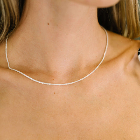 Close-up of a woman wearing a delicate silver necklace, highlighting simplicity and elegance in jewelry design.