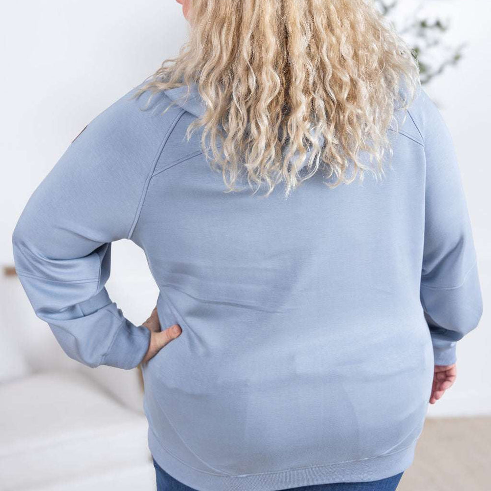 
                  
                    Back view of a model wearing the Scuba FullZip Hoodie in Dusty Blue, featuring a front zipper closure, cozy hood, and relaxed fit.
                  
                