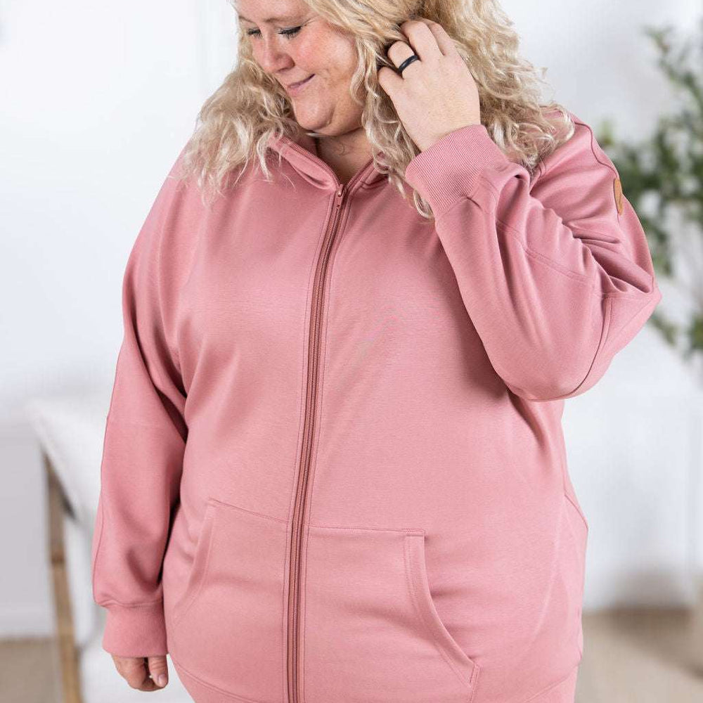 
                  
                    Close-up of a smiling model wearing the Scuba FullZip Hoodie in Rose, featuring a front zipper closure, cozy hood, and relaxed fit.
                  
                