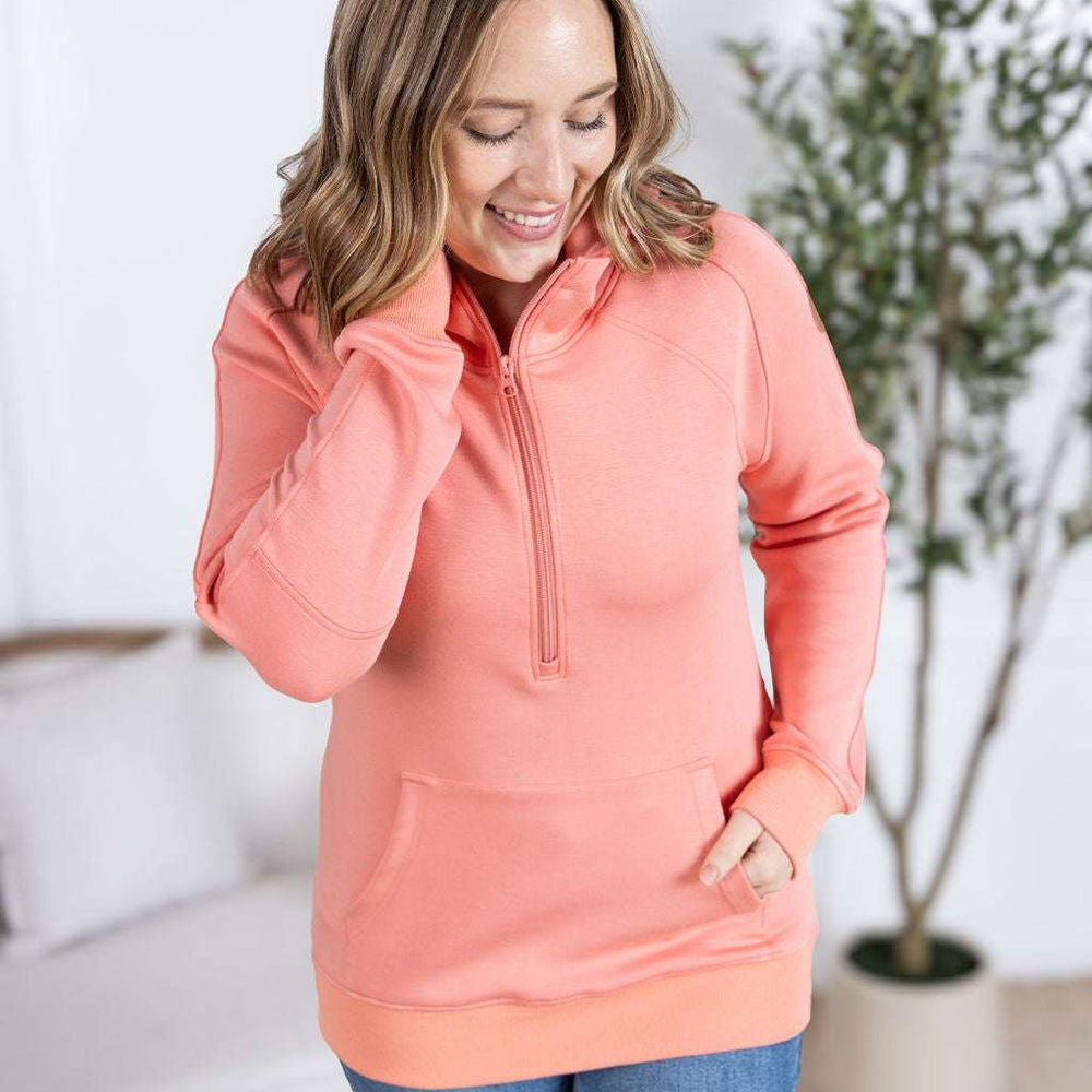 
                  
                    Close-up of a smiling model wearing the Scuba HalfZip Hoodie in Coral, featuring a half-zip neckline, cozy hood, and comfortable relaxed fit
                  
                