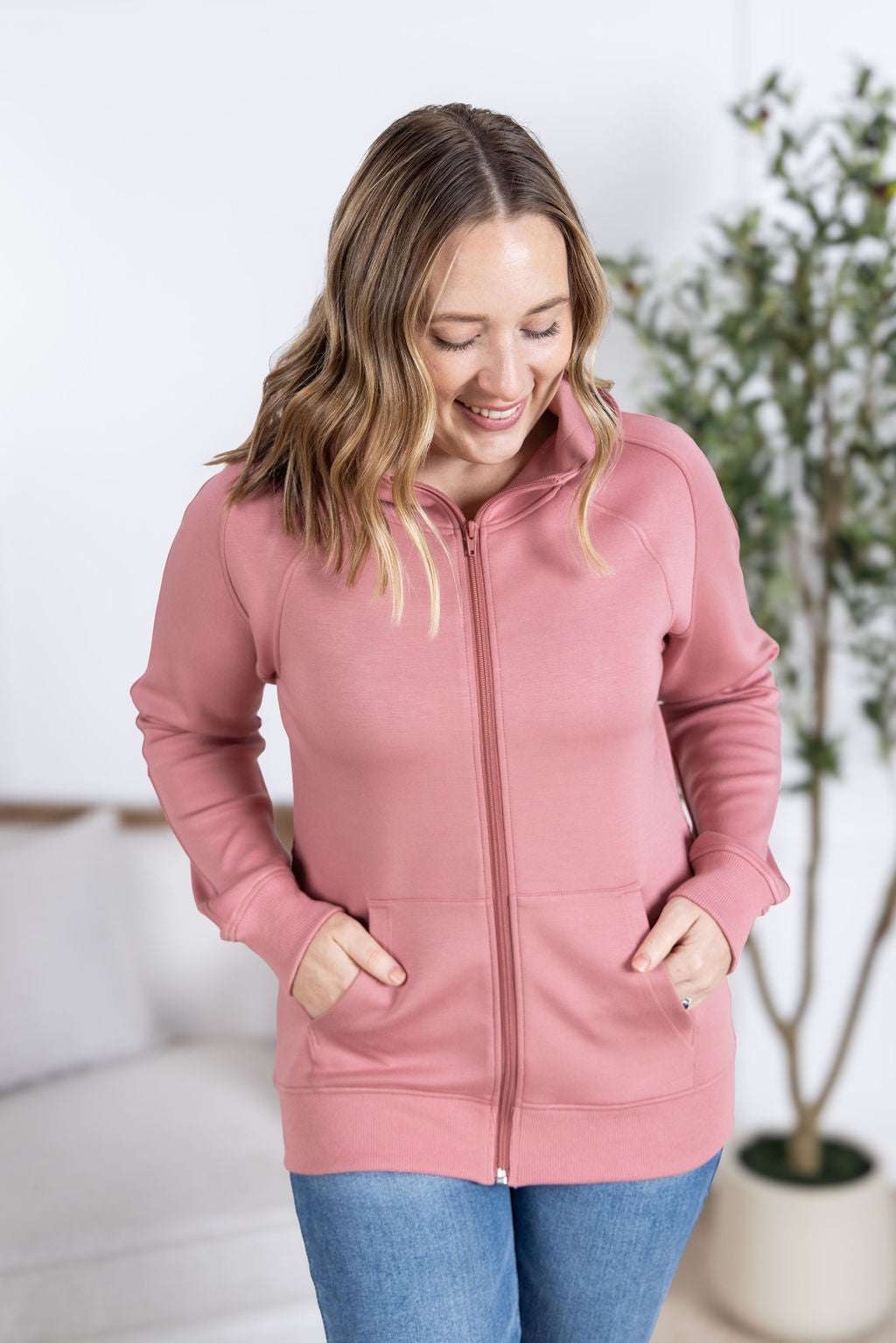 Close-up of a smiling model wearing the Scuba FullZip Hoodie in Rose, featuring a front zipper closure, cozy hood, and relaxed fit.