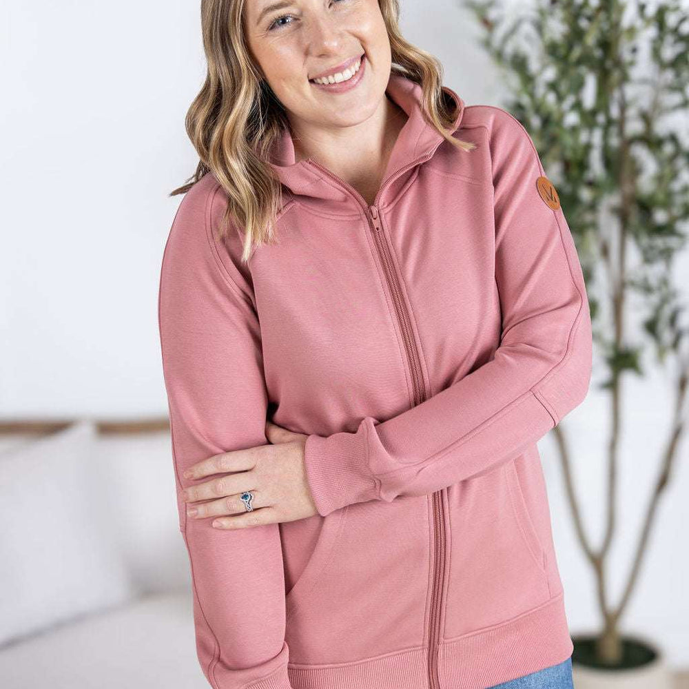 
                  
                    Close-up of a smiling model wearing the Scuba FullZip Hoodie in Rose, featuring a front zipper closure, cozy hood, and relaxed fit.
                  
                