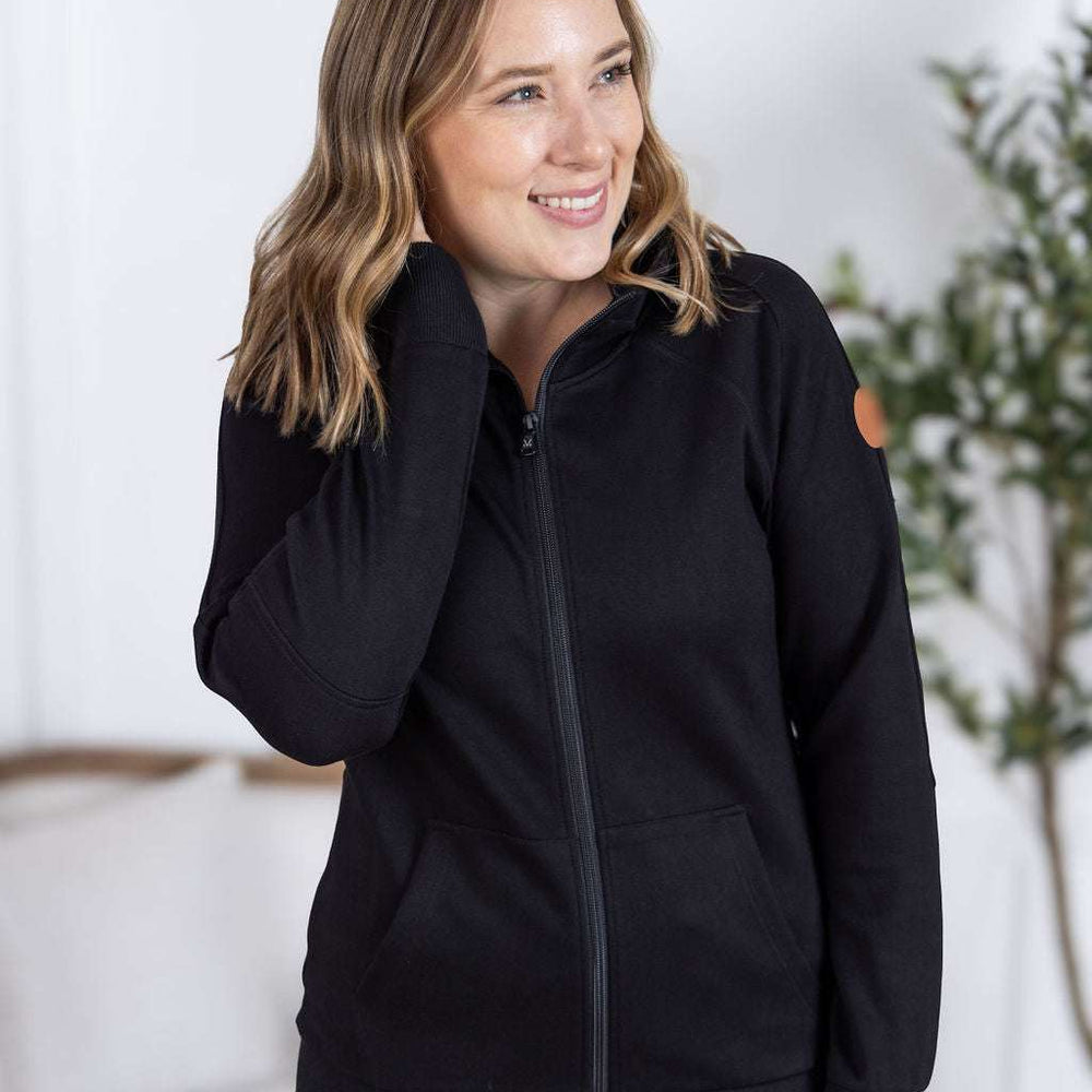 Close-up of a smiling model wearing the Scuba FullZip Hoodie in Black, featuring a front zipper closure, cozy hood, and relaxed fit.