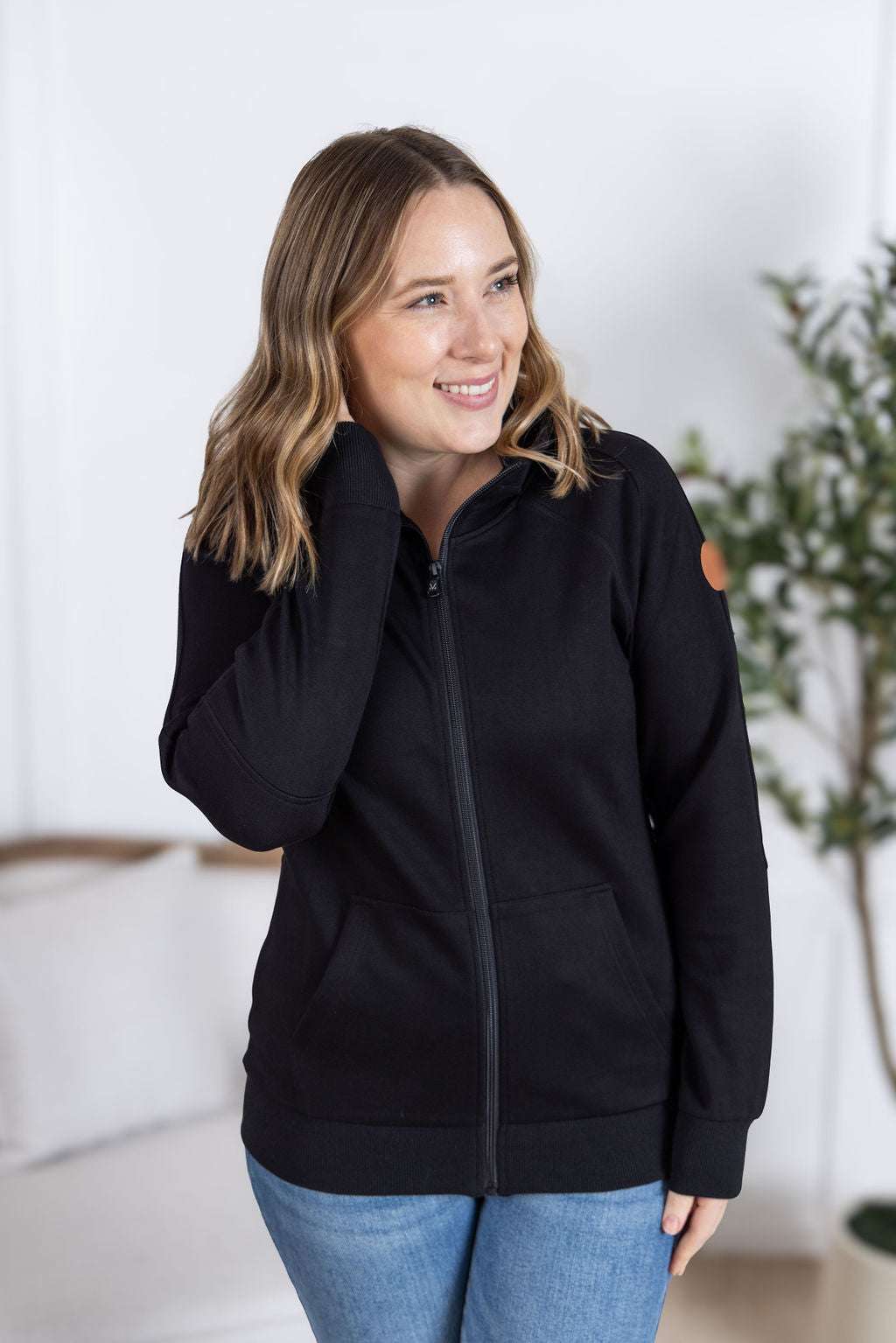 Close-up of a smiling model wearing the Scuba FullZip Hoodie in Black, featuring a front zipper closure, cozy hood, and relaxed fit.