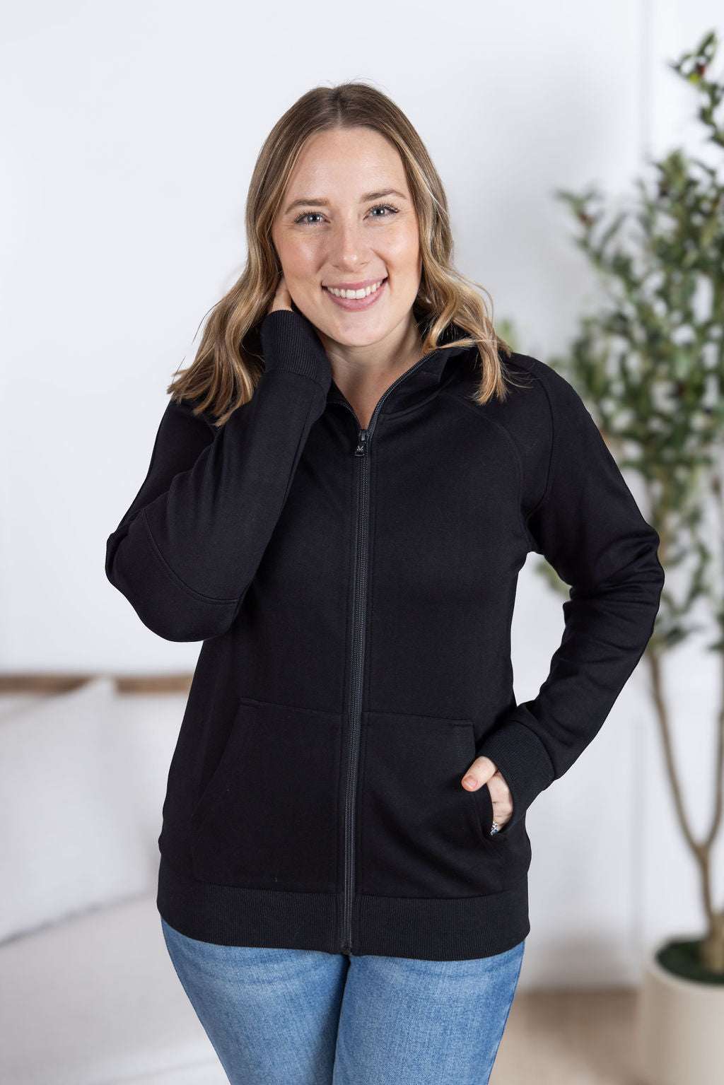 Close-up of a smiling model wearing the Scuba FullZip Hoodie in Black, featuring a front zipper closure, cozy hood, and relaxed fit.