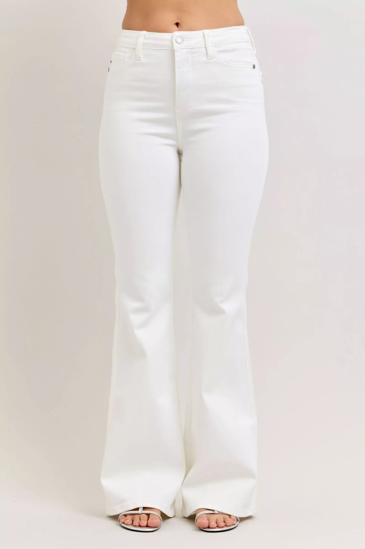 Woman wearing white high rise flare jeans with classic five-pocket styling and silver heeled sandals