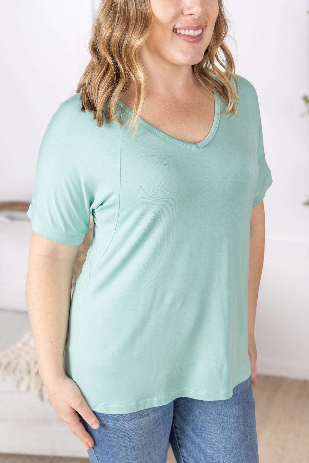 Close-up of a smiling model wearing the Bamboo V Neck Tee in mint by Michelle Mae, featuring a flattering v-neckline, short sleeves, and comfortable relaxed fit