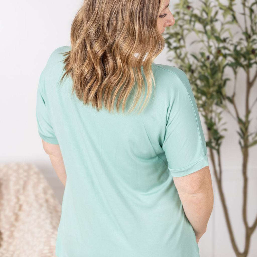 
                  
                    Close-up of a smiling model wearing the Bamboo V Neck Tee in mint by Michelle Mae, featuring a flattering v-neckline, short sleeves, and comfortable relaxed fit
                  
                