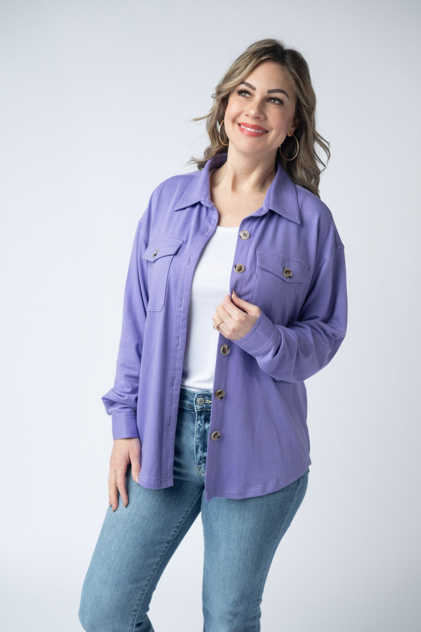 Woman wearing a lavender purple Brenna Button Down Top with breast pockets and button front, styled open over a white tank with jeans