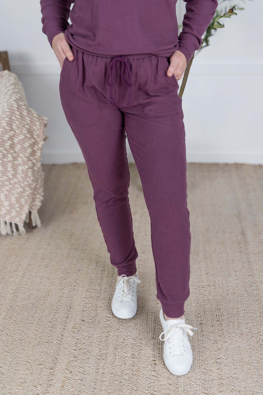 Model wearing the Corrine Joggers in Plum, featuring ribbed knit texture and drawstring waist.