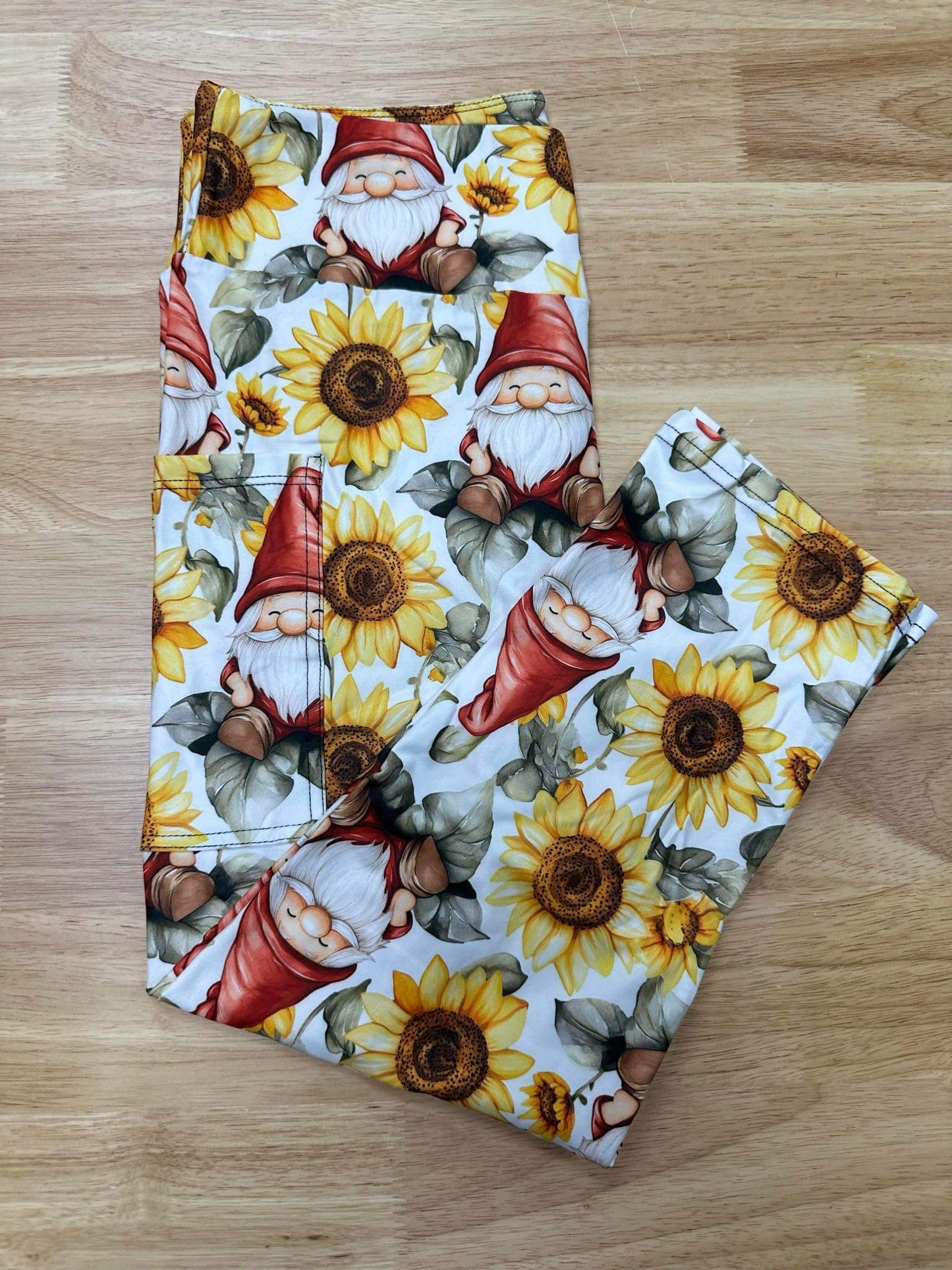 Folded sunflower gnome print leggings on wood background