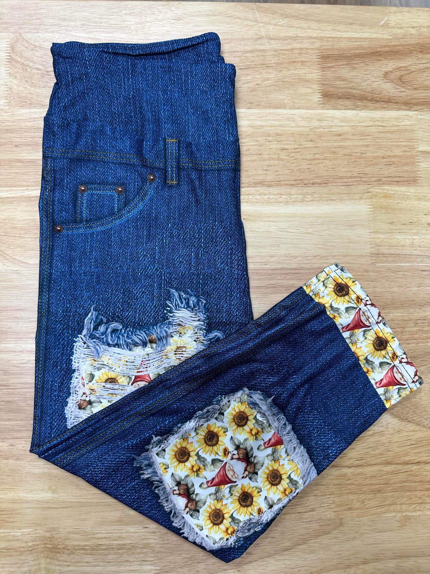Folded denim-look capri leggings with sunflower and gnome print patchwork and distressed accents
