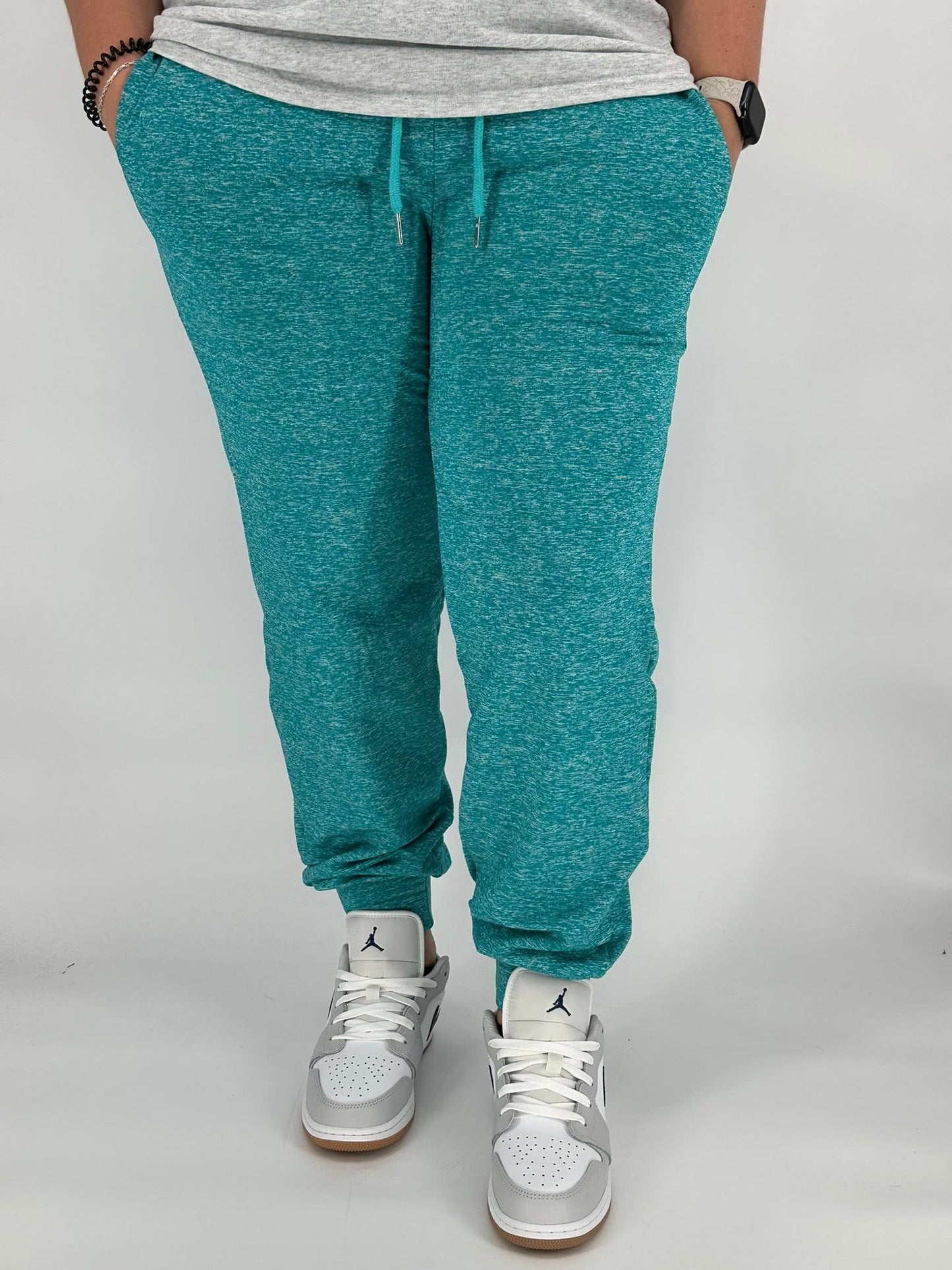 Model wearing heathered teal fleece-lined joggers with side pockets and elastic ankle cuffs