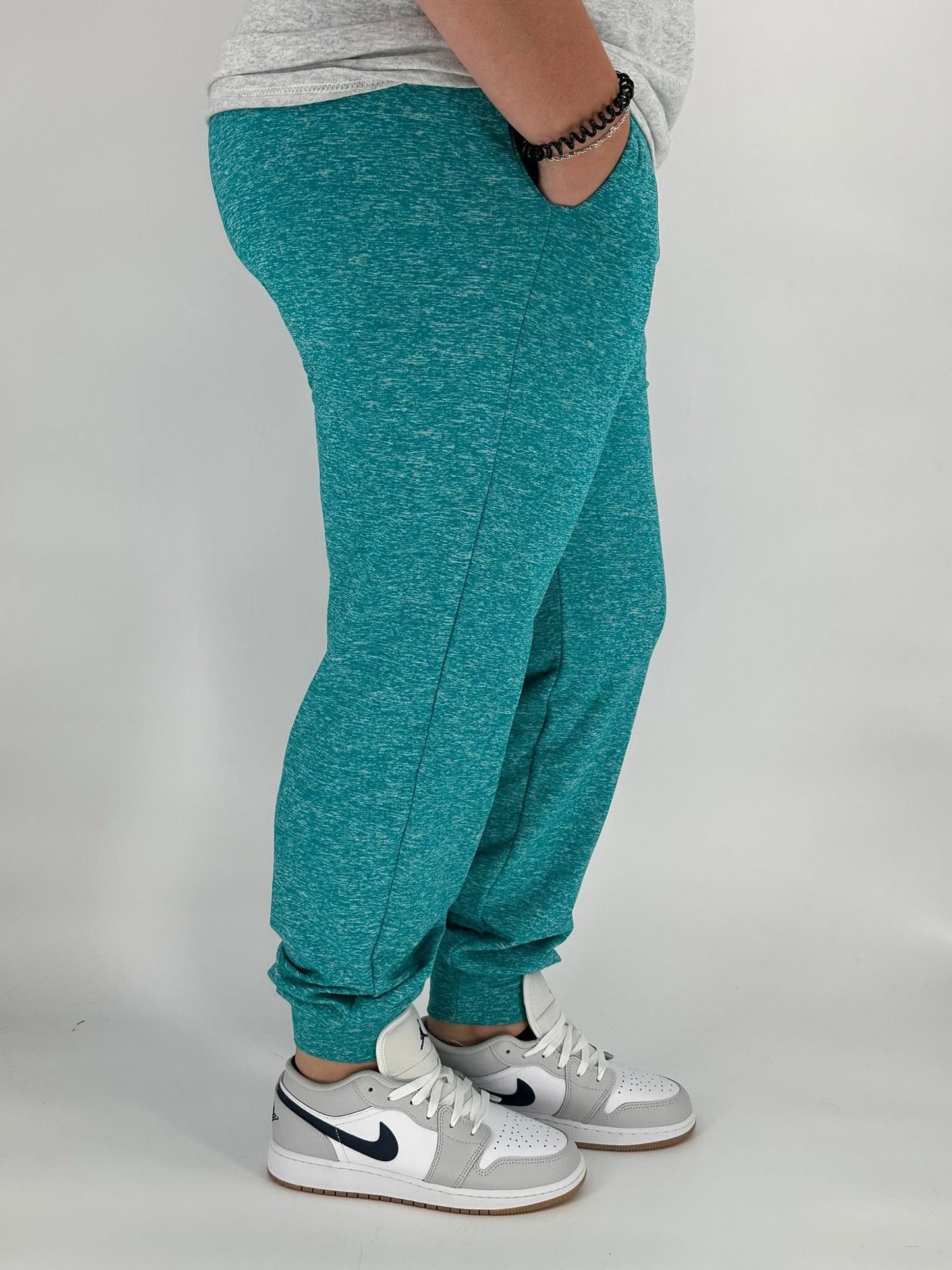 Model wearing heathered teal fleece-lined joggers with side pockets and elastic ankle cuffs