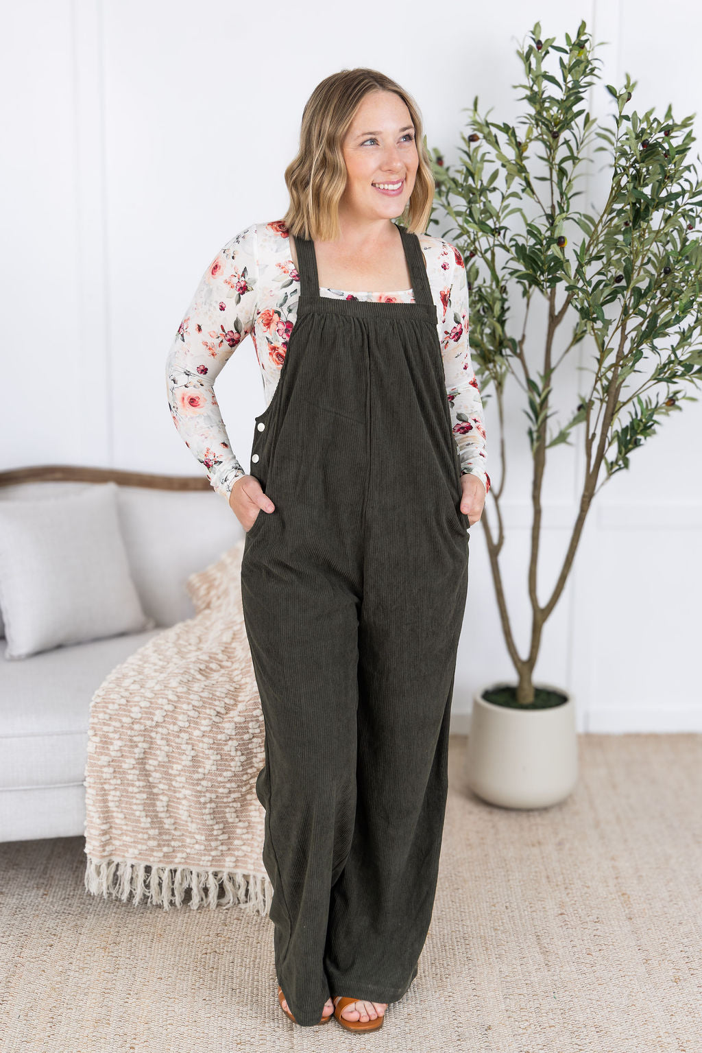 Woman wearing olive green corduroy overalls with floral top