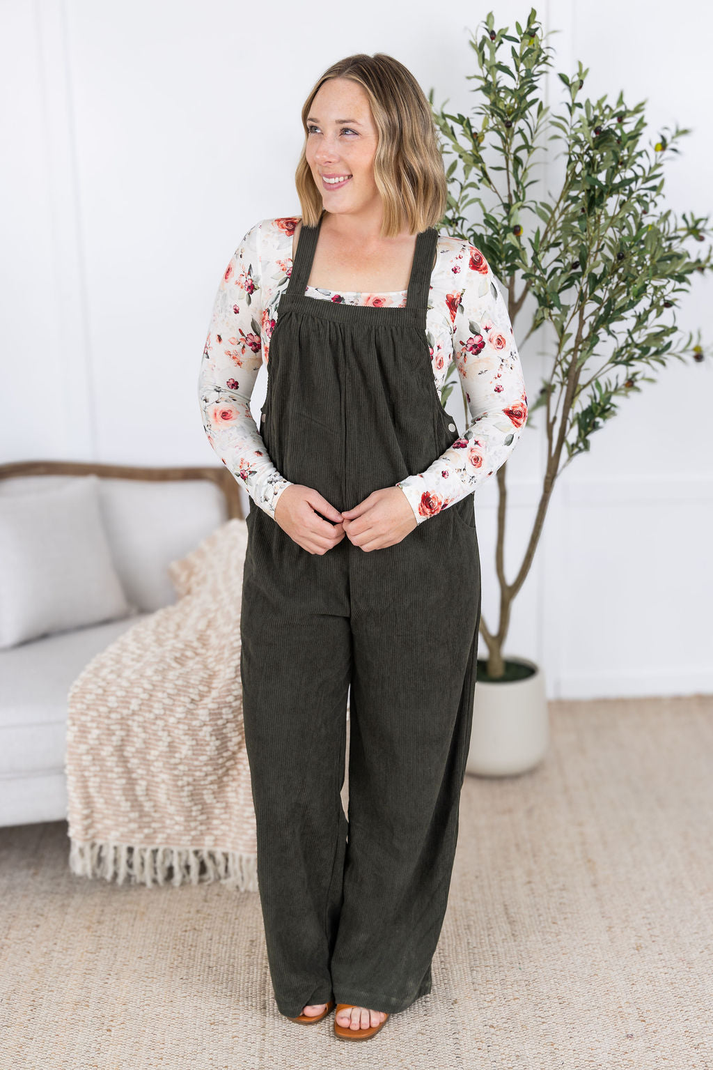 Woman wearing olive green corduroy overalls with floral top