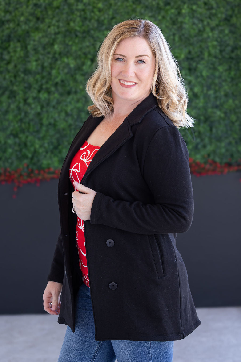 Woman wearing black sweater jacket with red top and jeans